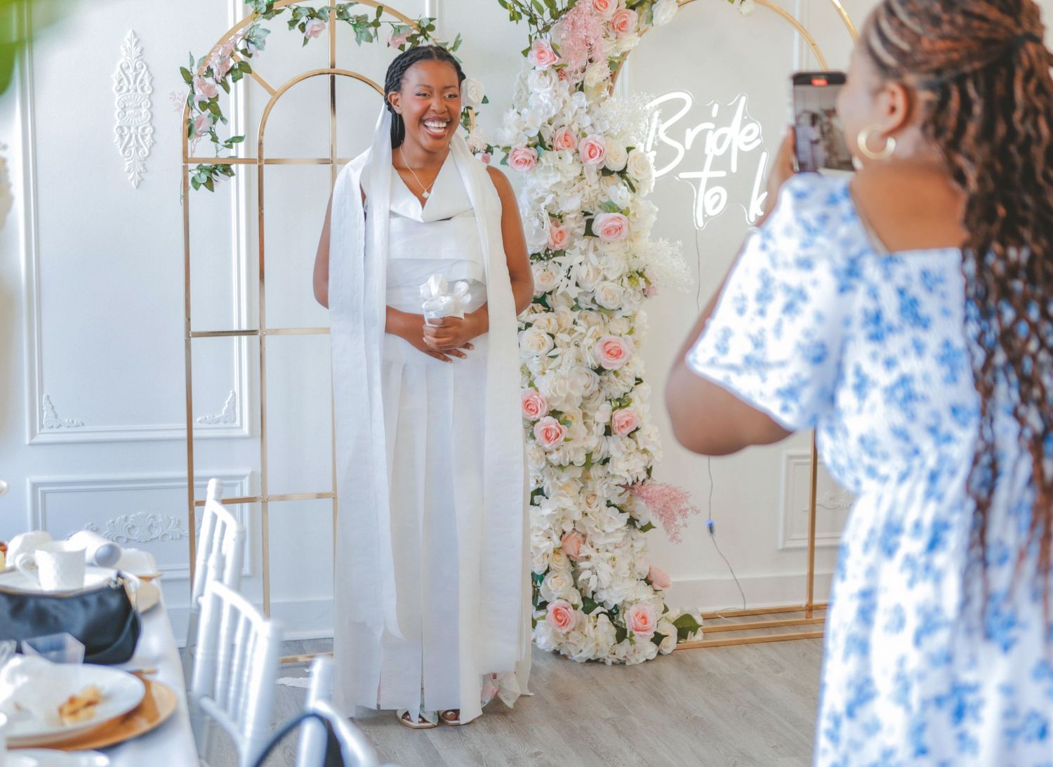 Bride-to-be standing in front of a floral backdrop at a bridal shower, captured in a clean and timeless style by a Calgary event photographe