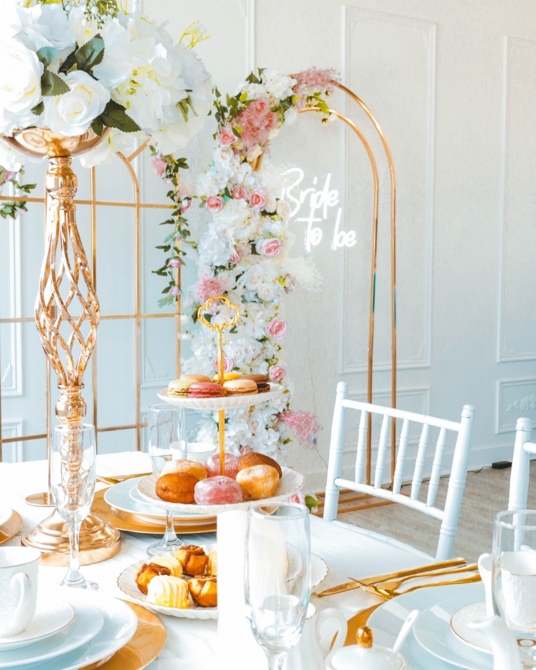Bridal shower setup with flowers, flowery arch, bride-to-be sign, and pastries on the table, captured by a Calgary event photographer