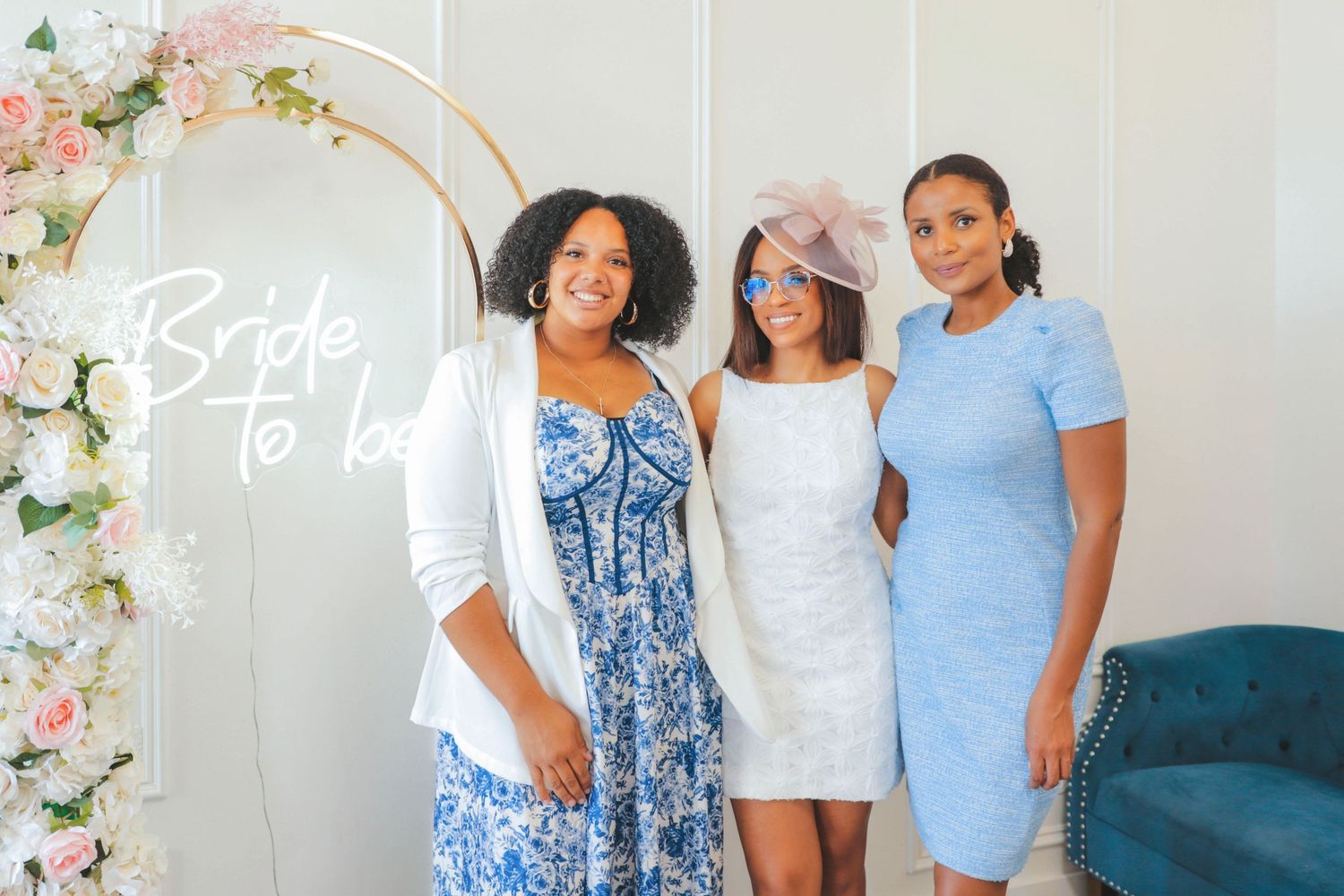 Three women posing in front of a floral arch with “Bride to Be” signage at a bridal shower in Calgary