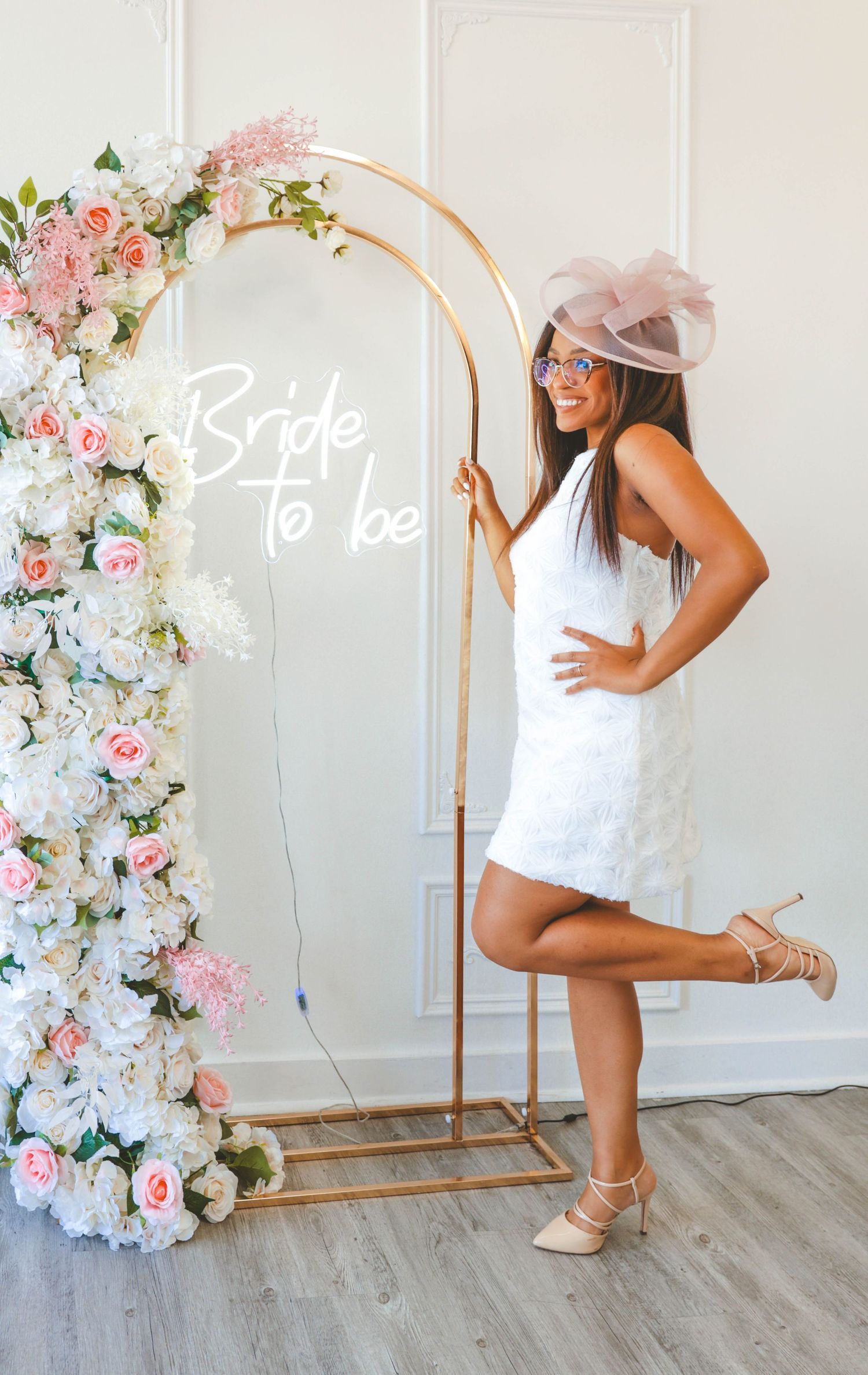 Bride-to-be posed in front of a floral arch with a bride-to-be sign, captured by a Calgary event photographer