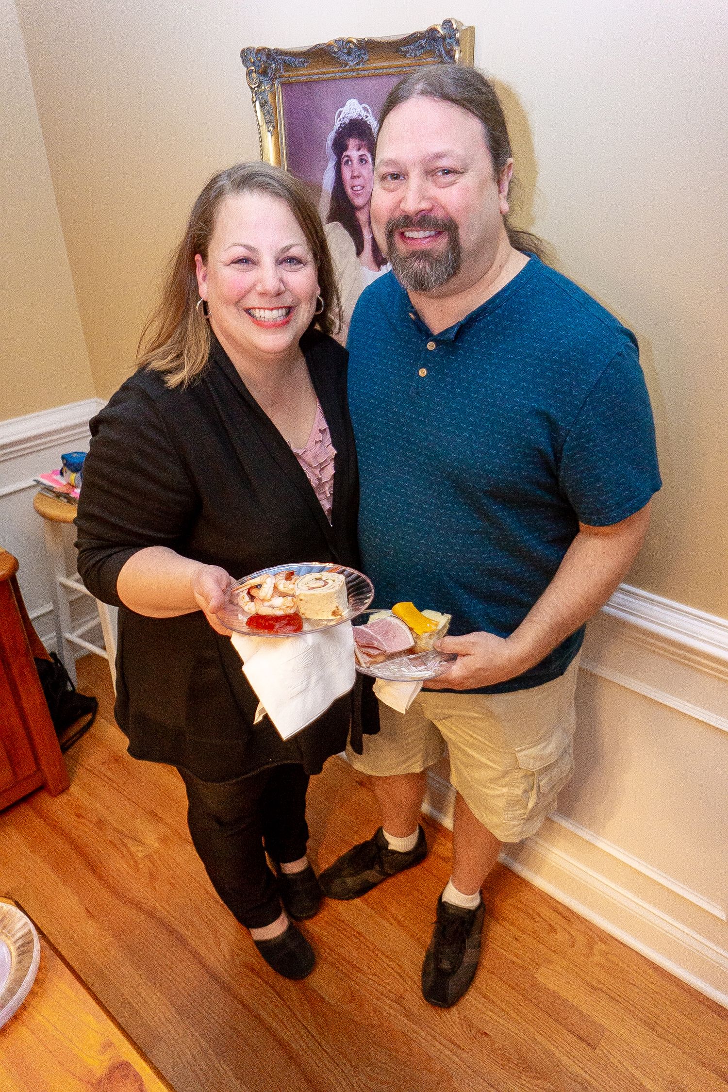 Two people pose together on hardwood flooring during a casual indoor gathering.