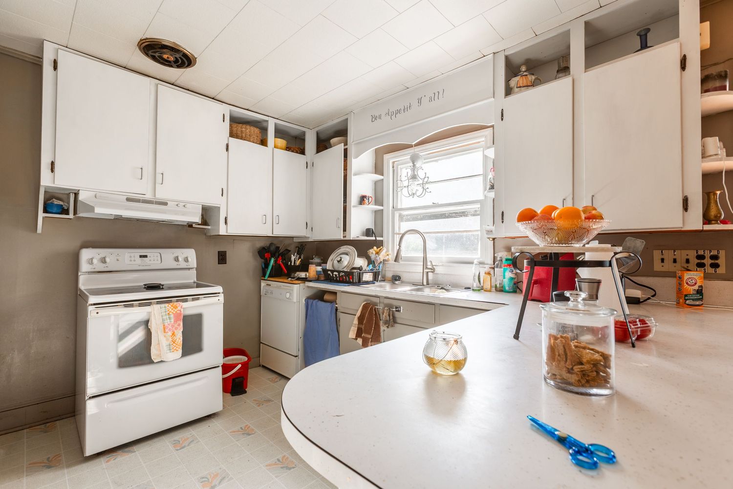 Modern white kitchen with clean lines, stainless steel appliances, and expansive countertops in natural lighting.