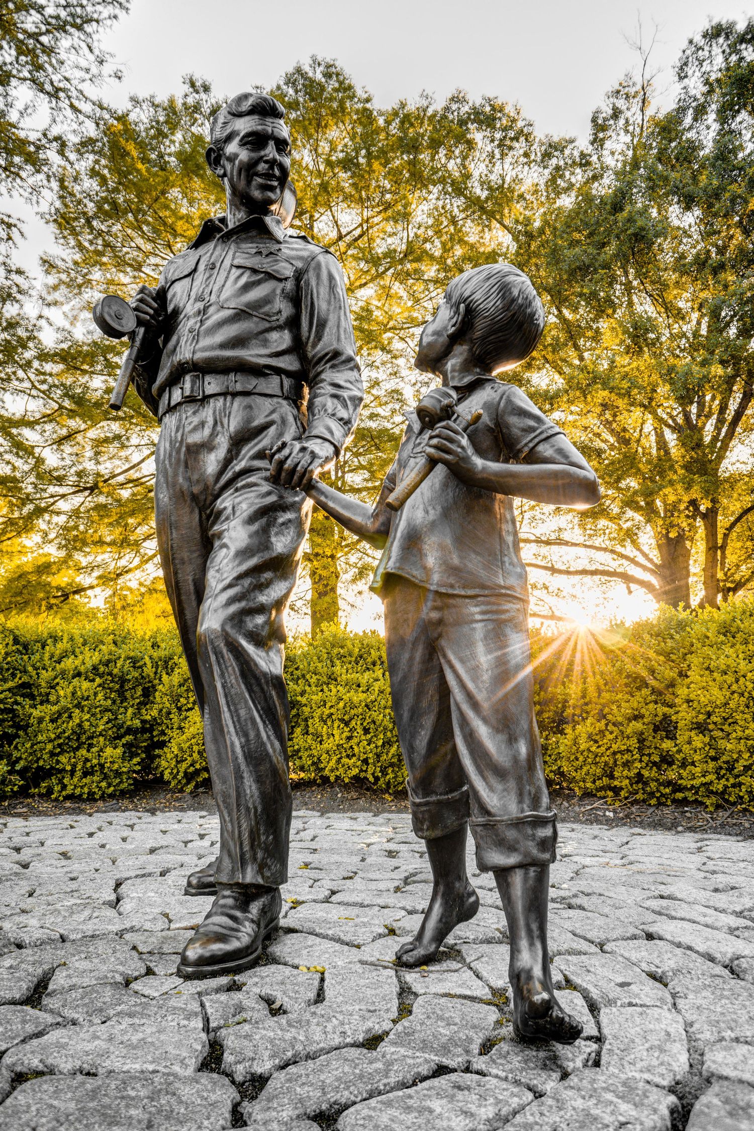 Bronze statue of Andy Griffith and Opie Taylor holding hands at sunset in Pullen Park, Raleigh, NC.