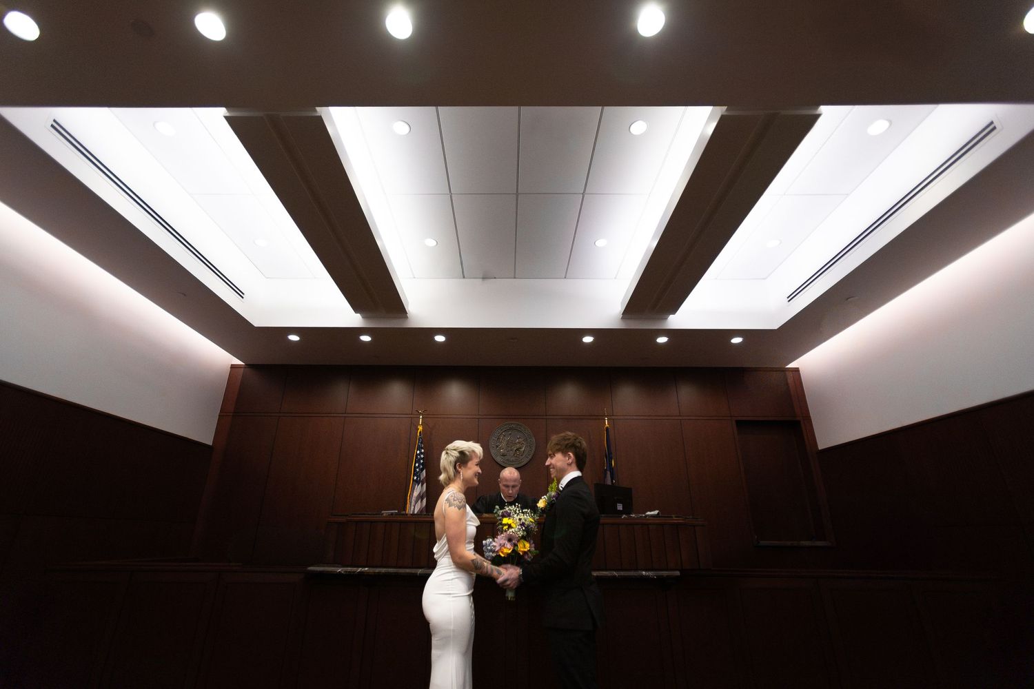 Wedding ceremony venue with modern lighting and dark wood paneling on the ceiling.