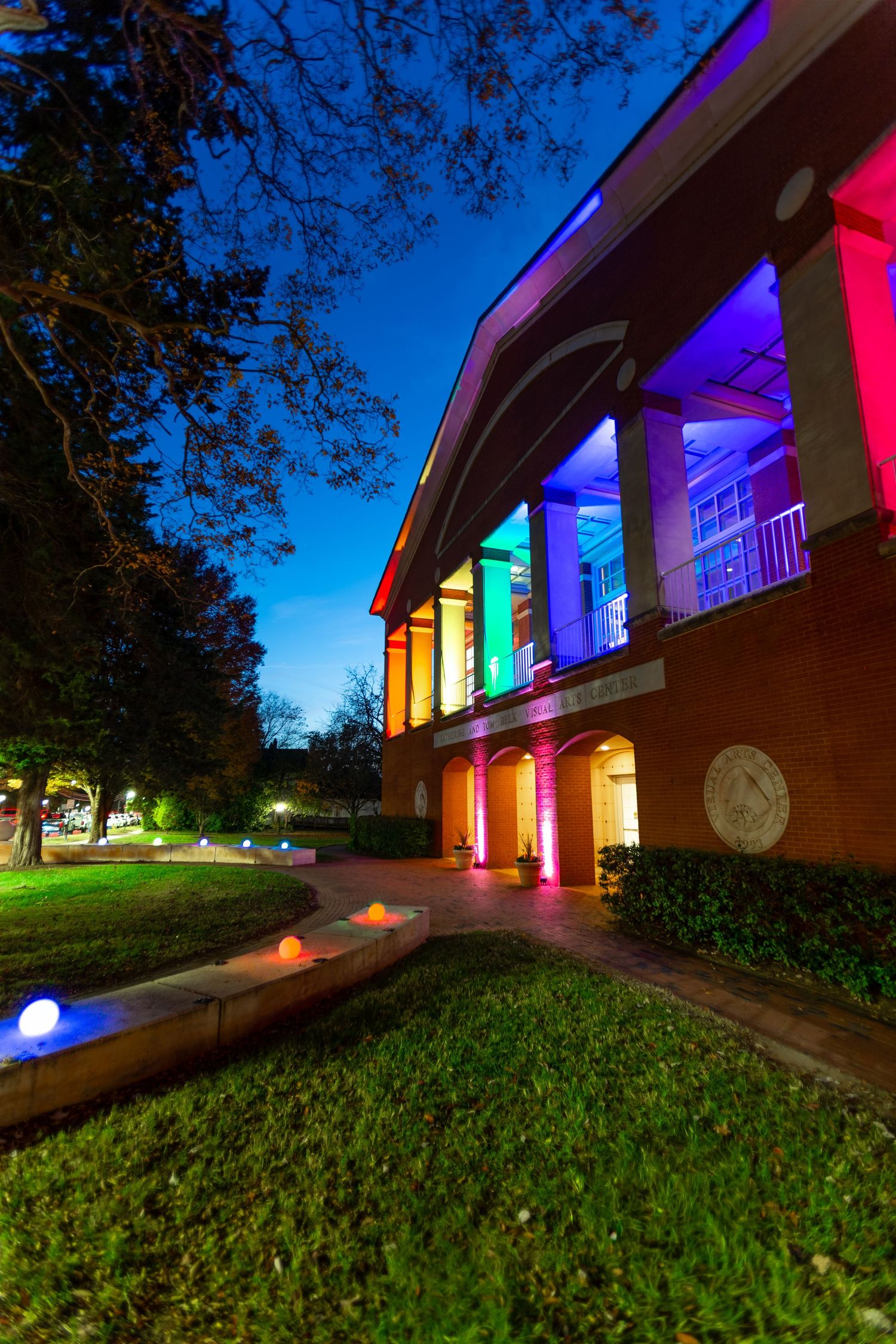 Building exterior illuminated with colorful LED lights creating a rainbow effect at night.