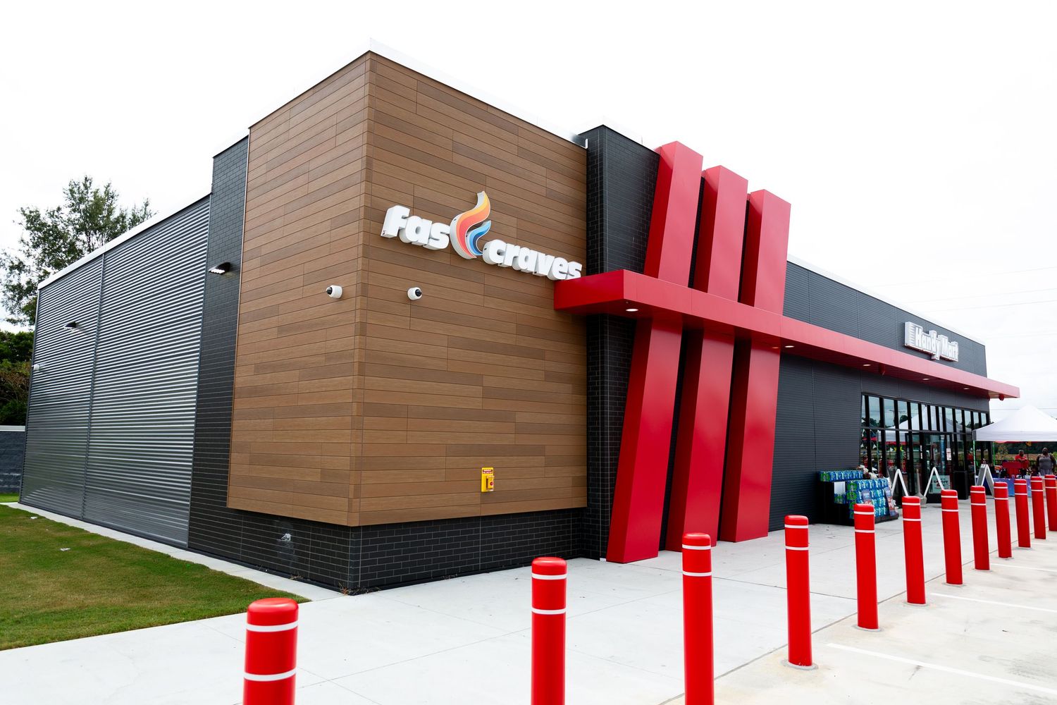 Modern commercial building exterior with distinctive red architectural columns and wood panel accents.