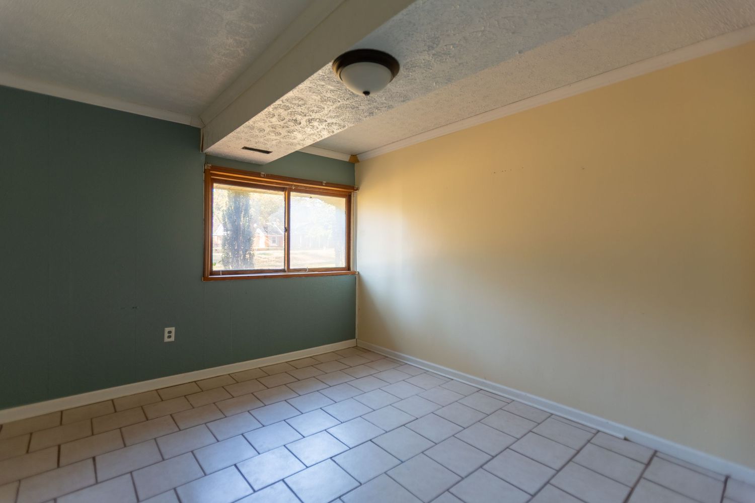 Empty interior room with beige walls, white trim, and tile flooring showing a corner view.