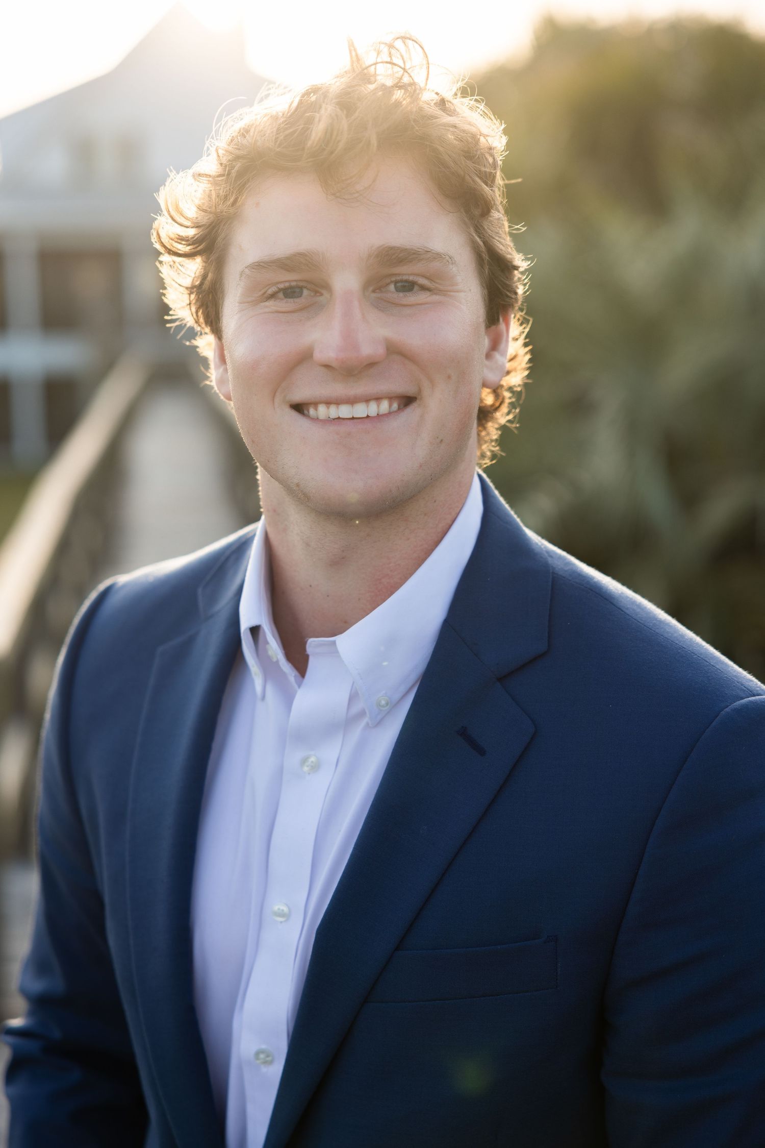Professional headshots of a person in a navy suit and white shirt against a blurred background.