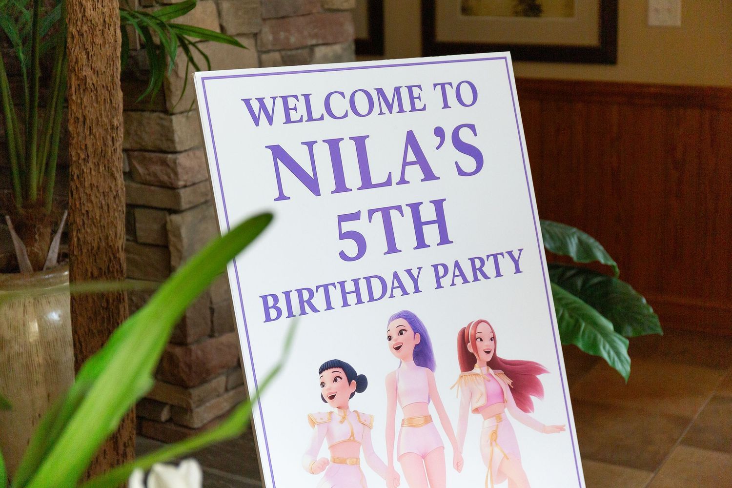 Welcome sign for Nila's birthday party with decorative illustrations displayed on an easel.