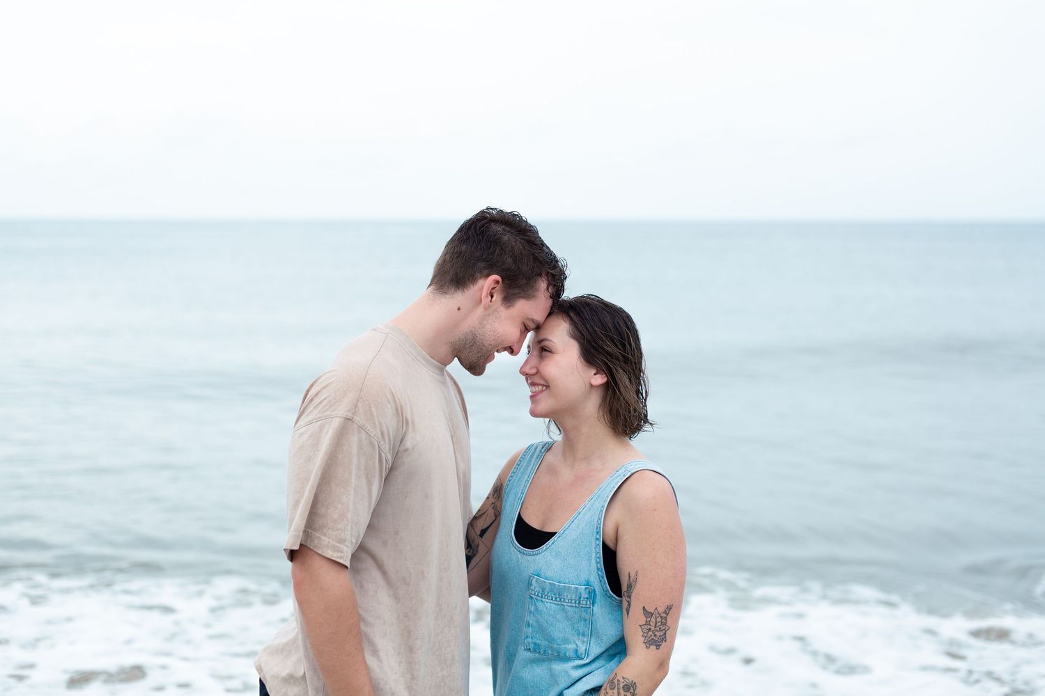 Romantic couple sharing an intimate moment by the ocean on a cloudy day.