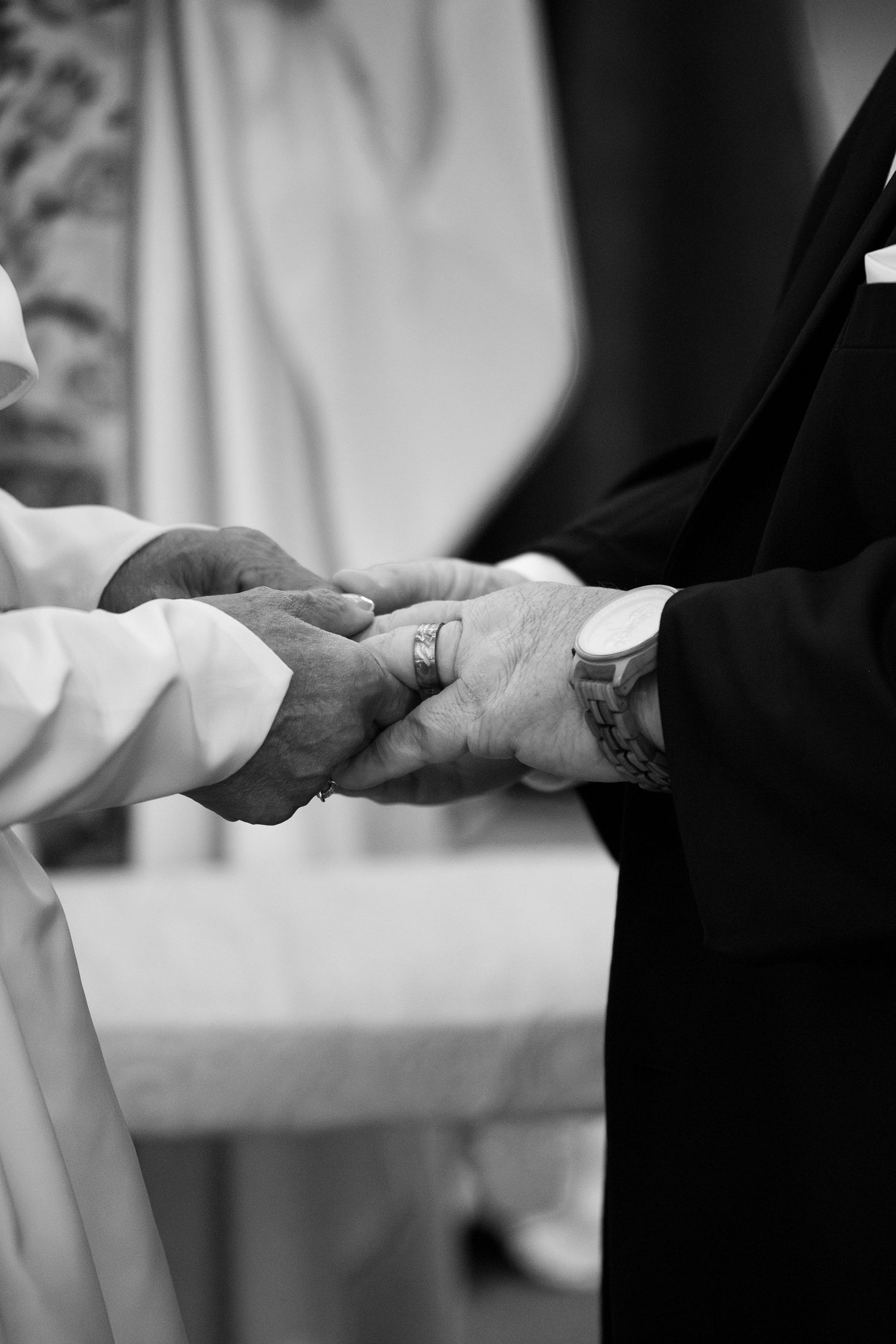 Black and white close-up of hands exchanging wedding rings during a traditional marriage ceremony.