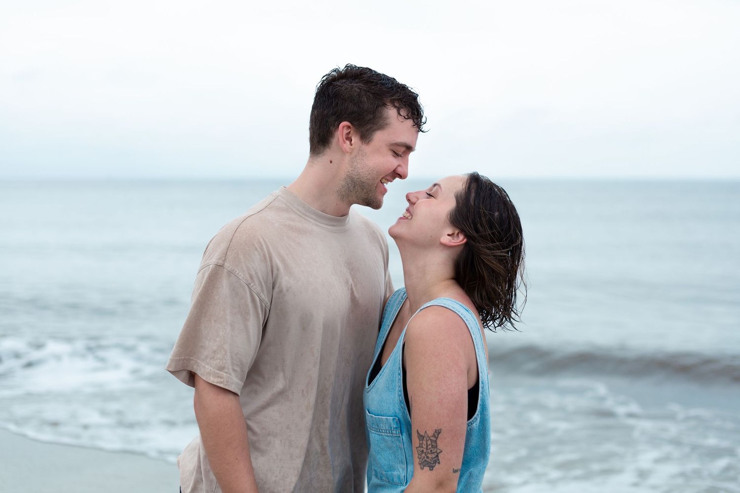 Romantic couple embracing and sharing intimate moments on a misty beach with ocean waves in background.