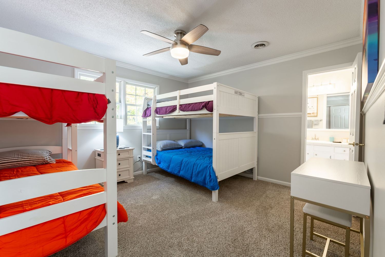 Modern apartment interior with white walls, ceiling fan, and carpeted floors showing multiple bedrooms.