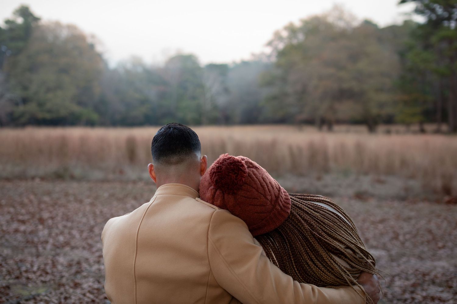 Two people walking together through a scenic autumn field at sunset.