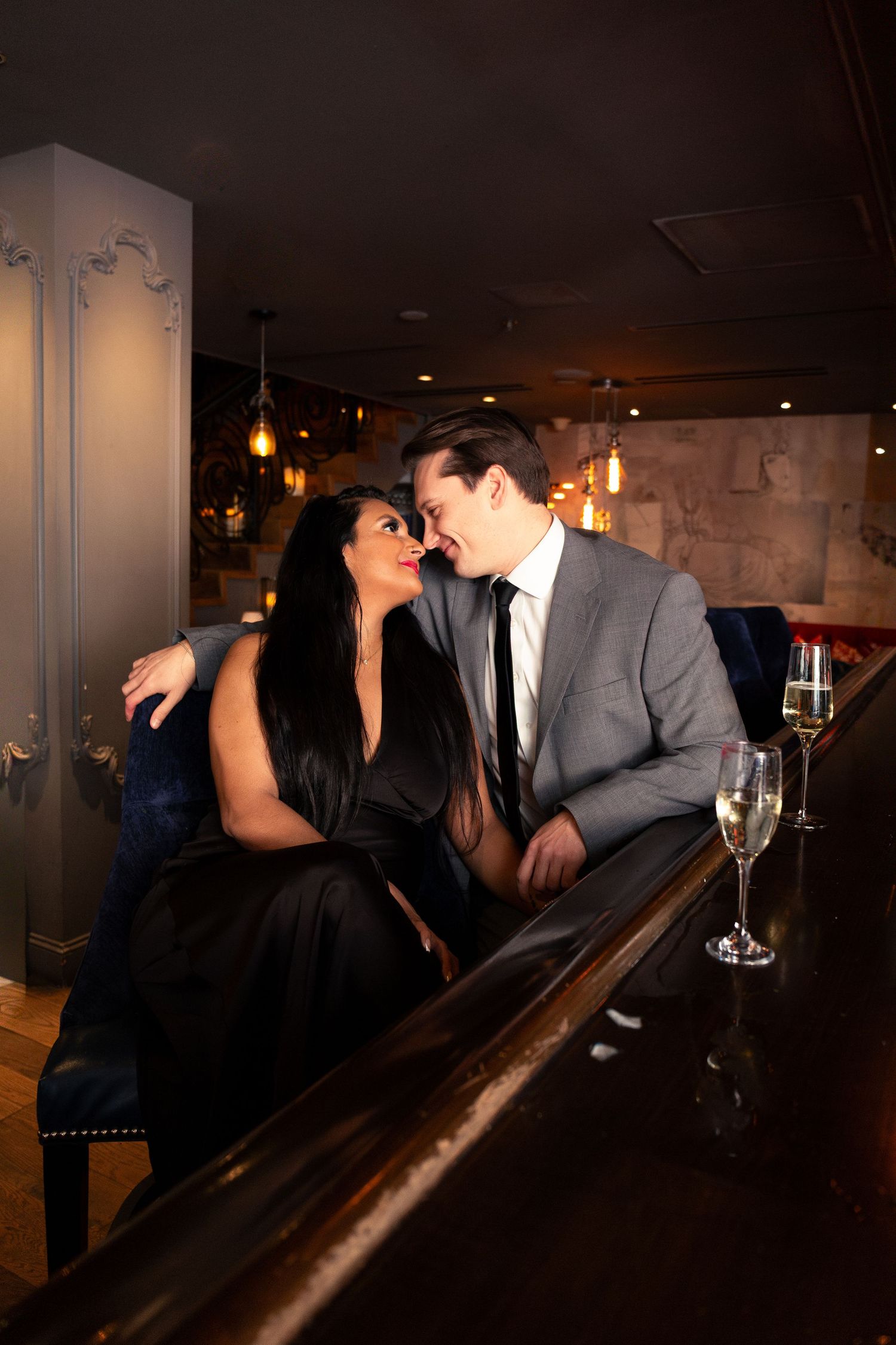 Romantic couple in formal attire share intimate moments at dimly lit restaurant bar in progressive photo series.
