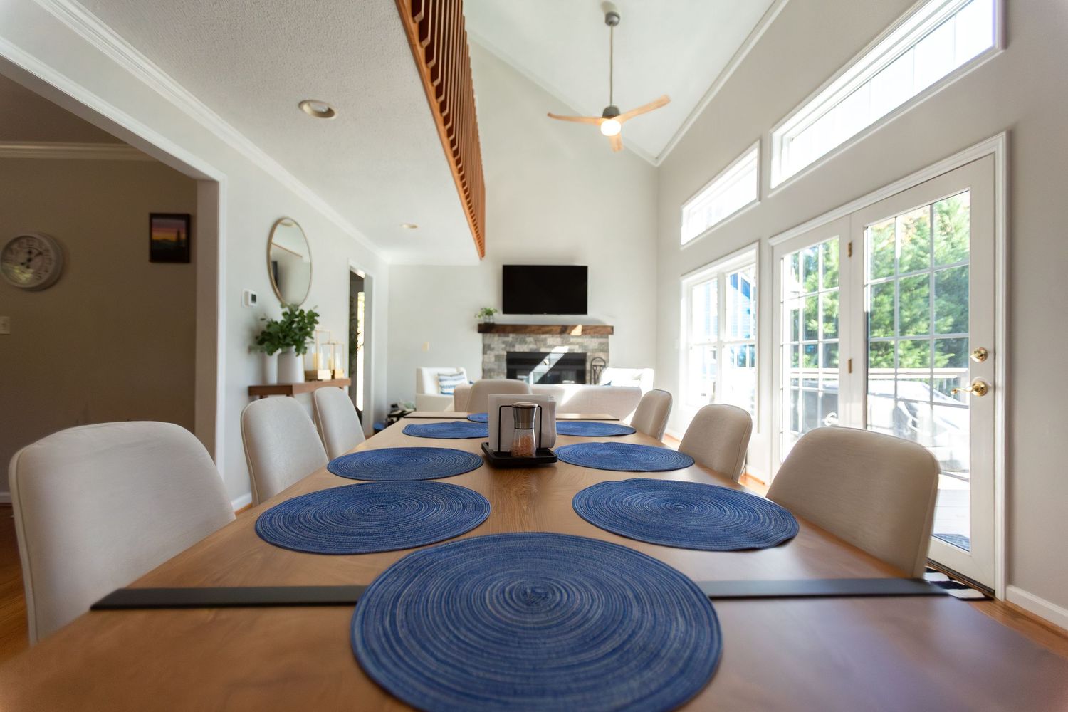 Bright interior room with vaulted ceilings, exposed beams, and blue circular placemats on a wooden dining table.