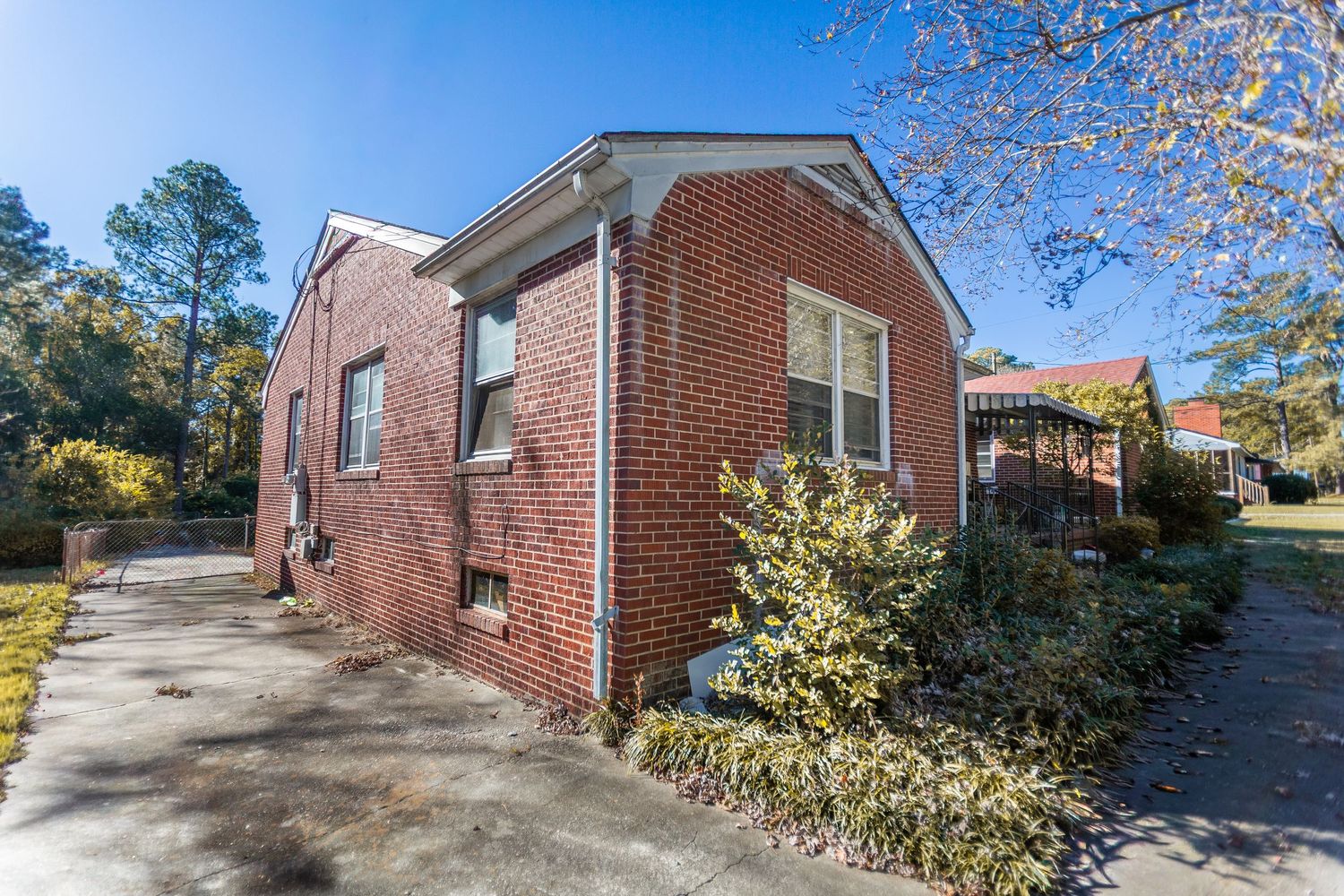 Exterior view of a brick ranch-style house with autumn trees and landscaping in the yard.