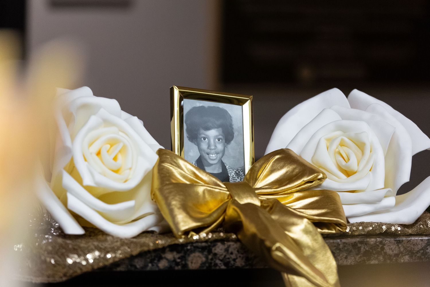 White roses with gold ribbon decorations arranged for an elegant event setting.