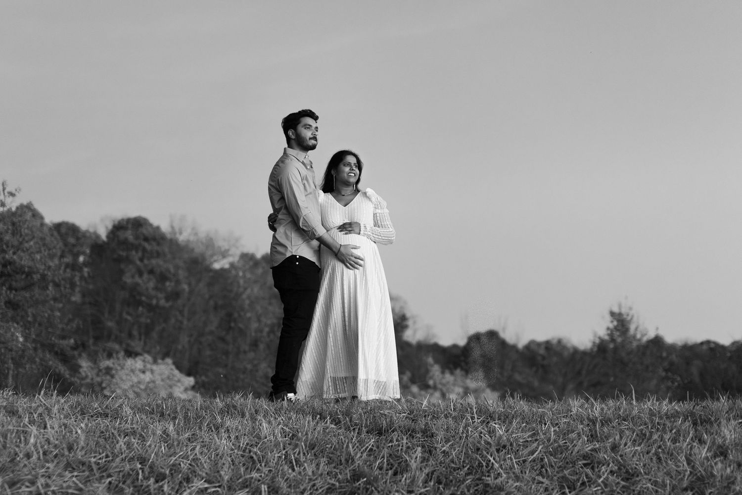 A black and white photo series shows people dancing joyfully in a meadow on a sunny day.