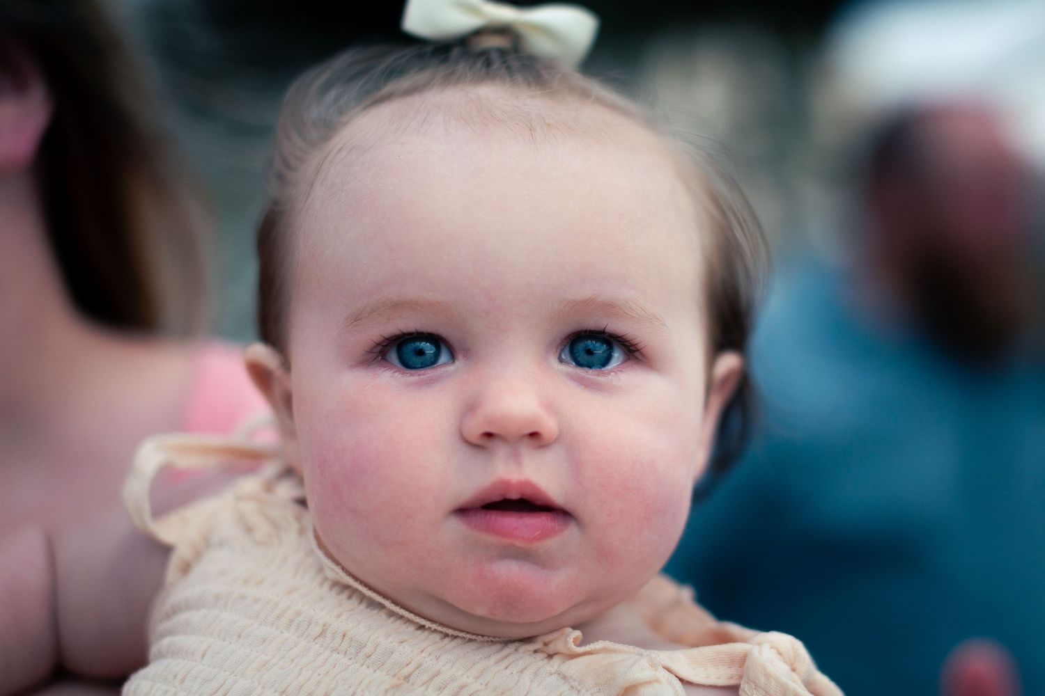 Close-up portrait of a baby with bright blue eyes and rosy cheeks.