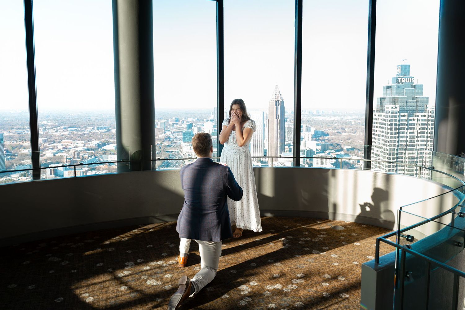 Visitors enjoy panoramic city views through floor-to-ceiling windows in a modern observation deck.
