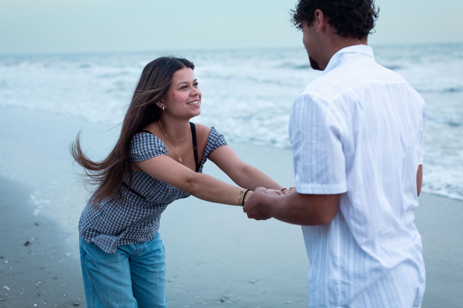 A couple shares a romantic moment while walking together on a sandy beach at sunset.