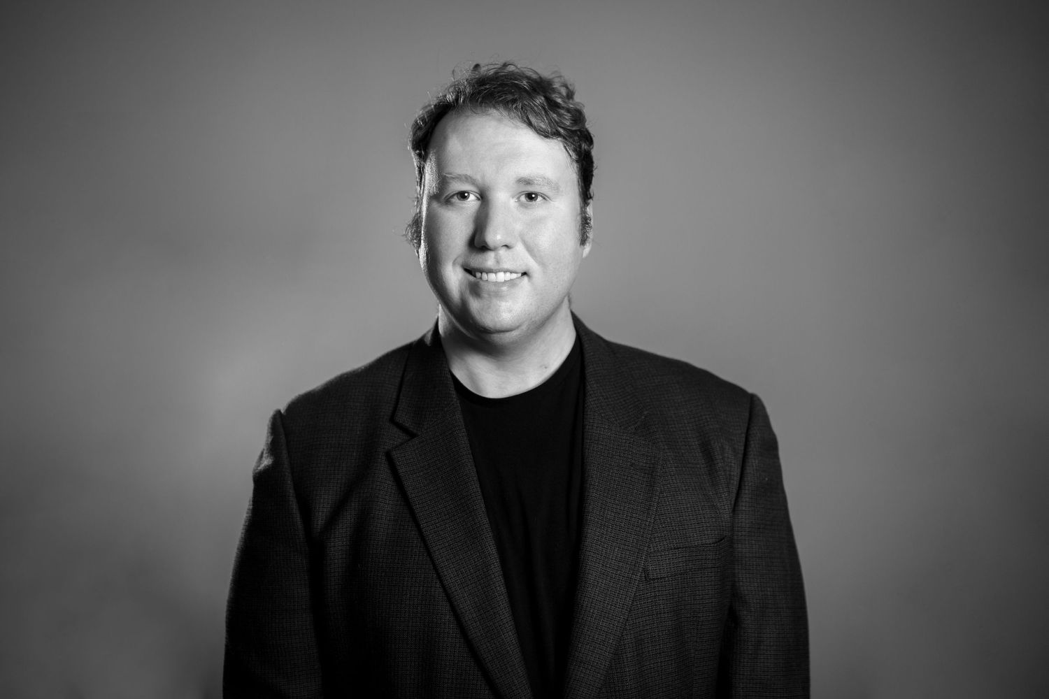 Professional headshot series in black and white against neutral studio background.