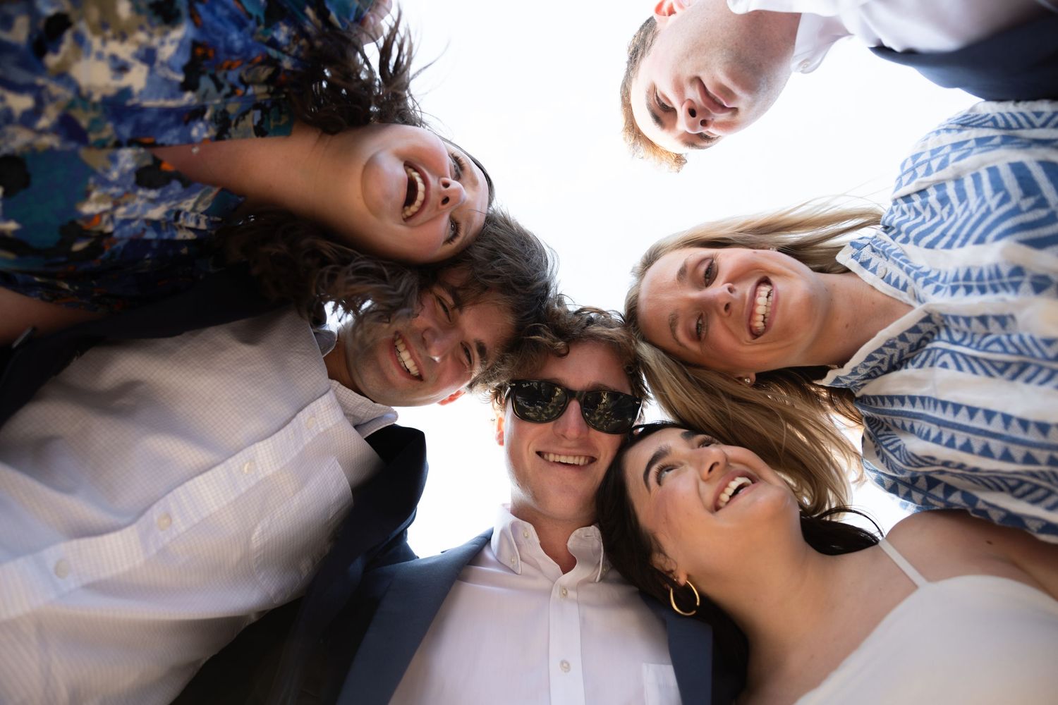 Friends laying down together in a circle formation looking up at the camera.