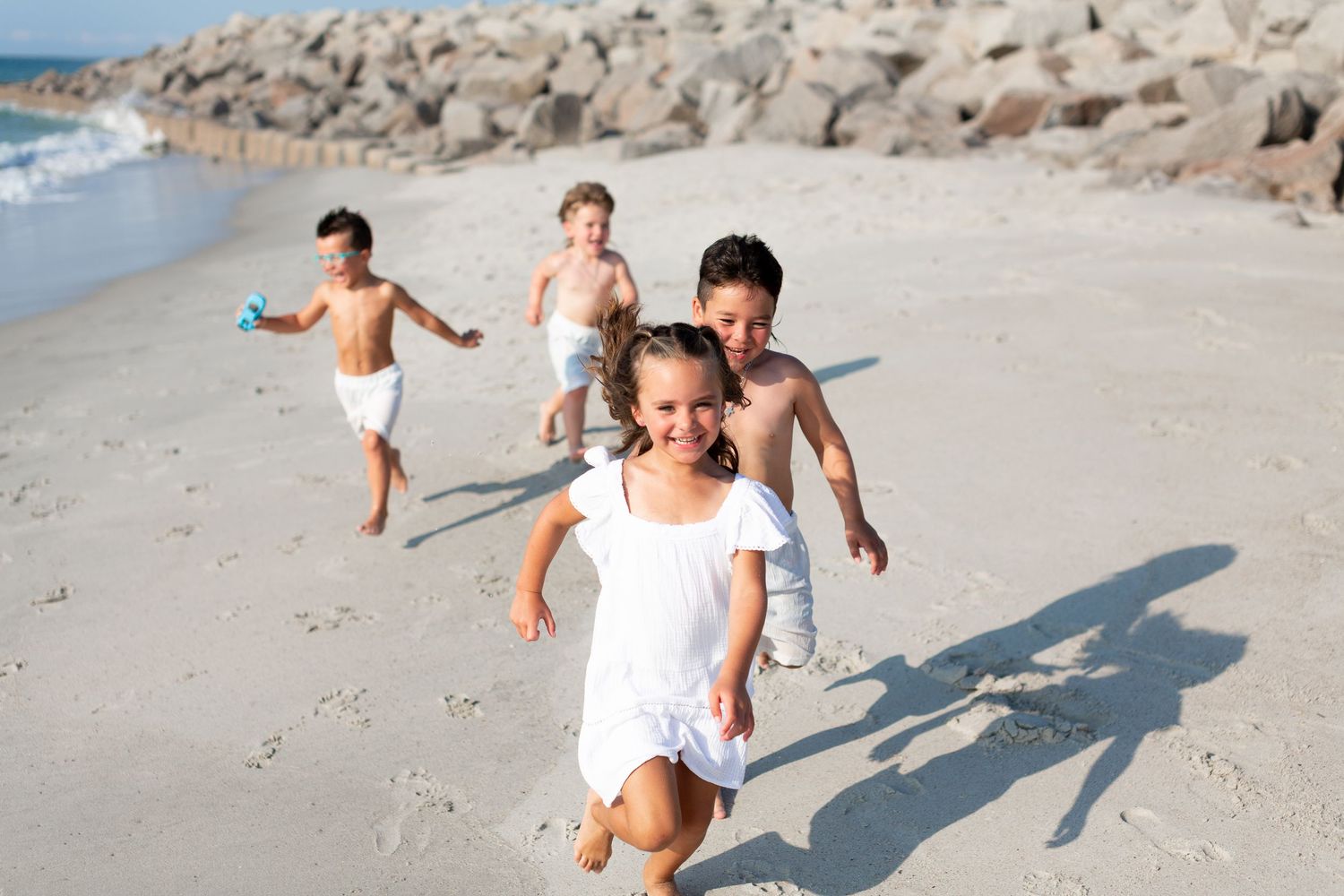 Candid beach moments with people running and playing in white outfits.