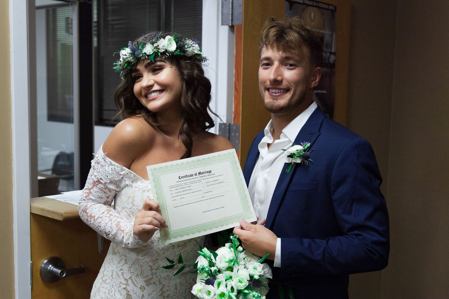 Wedding party members holding documents and floral bouquets during an indoor celebration.