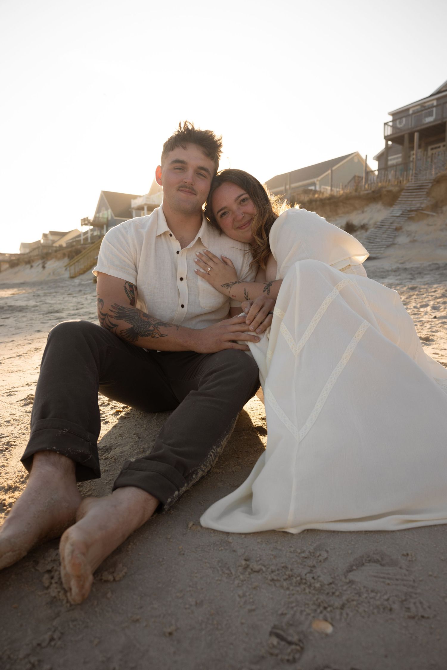 Couple relaxing on a sandy beach at sunset in romantic poses.