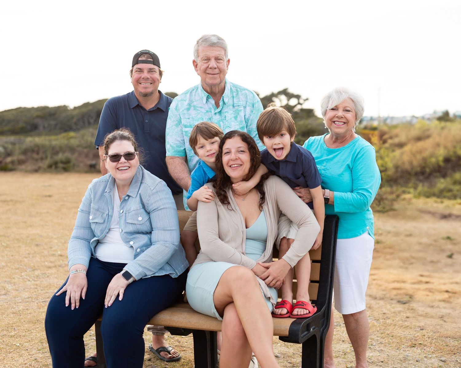 Multi-generational family gathers outdoors for casual portrait session at golden hour.