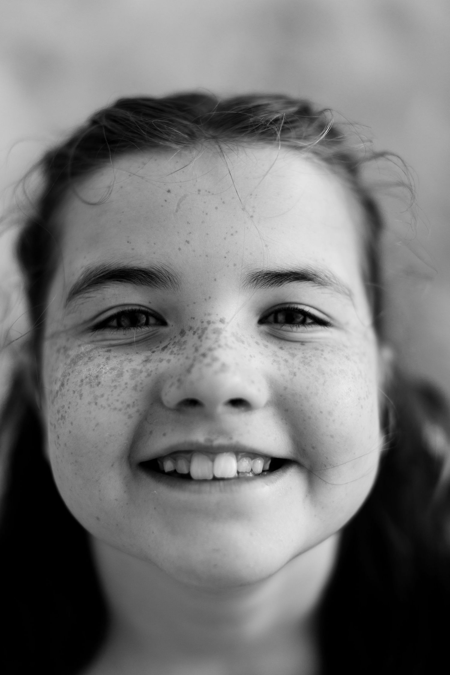 A series of black and white close-up photos showing bright smiles and joyful expressions.