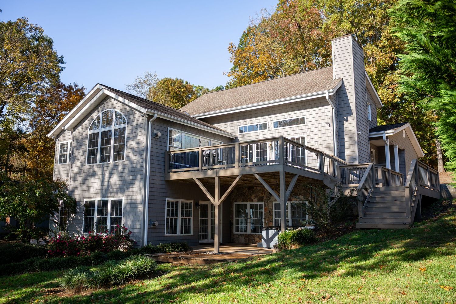 Exterior view of a modern gray residential home with multiple levels nestled among trees on a hillside.