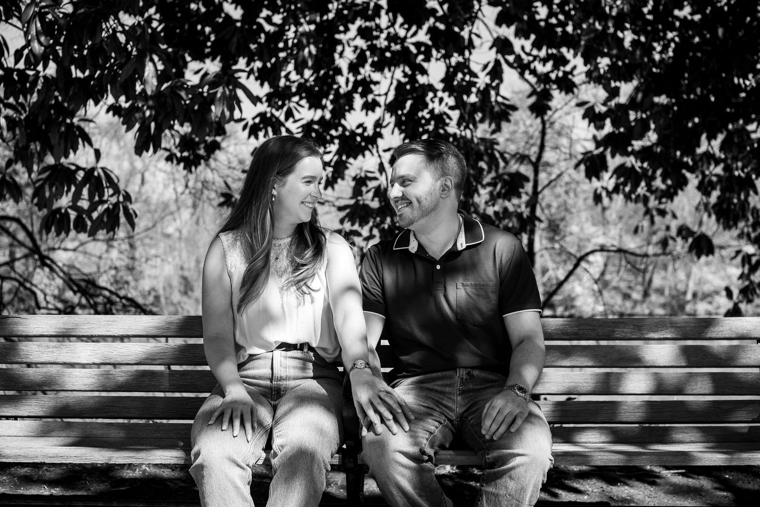 A black and white photo series showing a couple sitting together on a bench in a park setting.