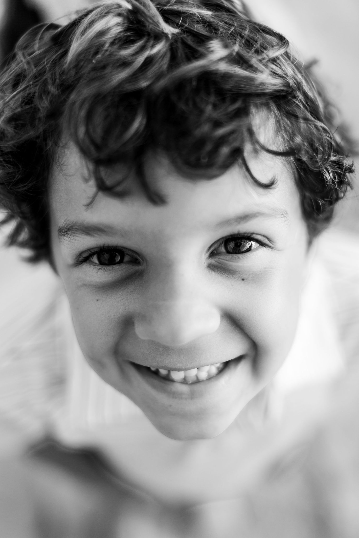 Black and white close-up portrait showing bright smile and curly hair.