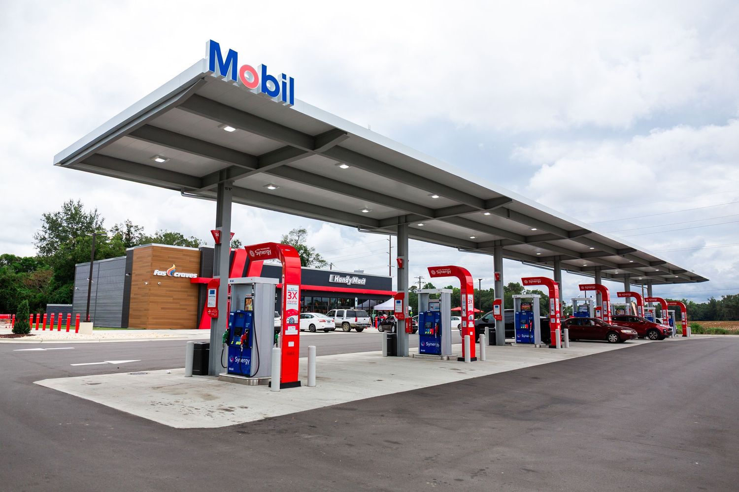 Modern Mobil gas station with multiple red and white fuel pumps under a covered canopy area during daytime.