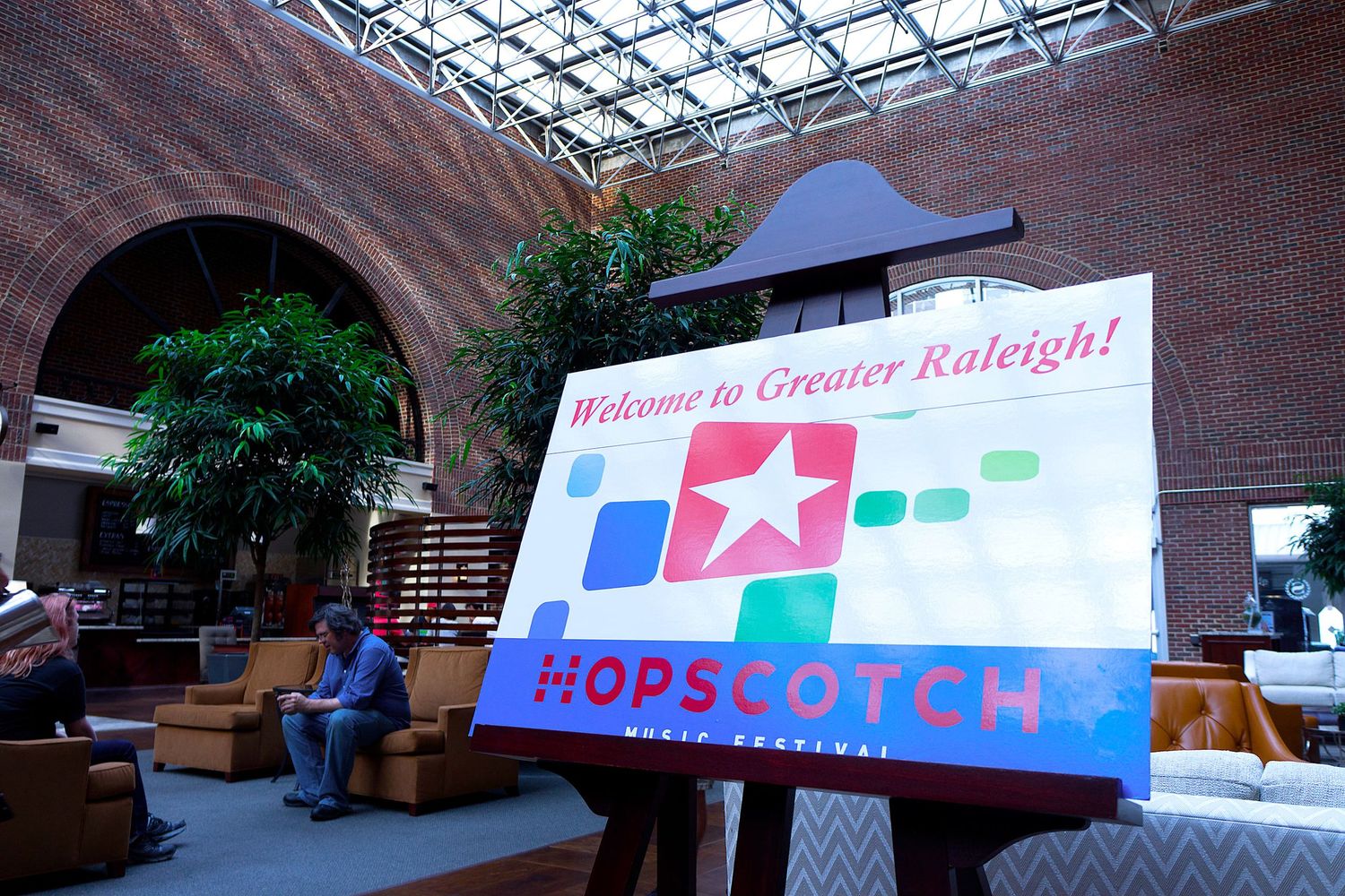 Welcome banner displayed under a glass ceiling in a brick building atrium.