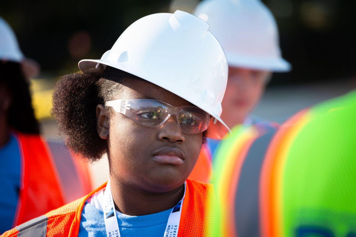 Construction workers in hard hats and safety vests stand together at a worksite.