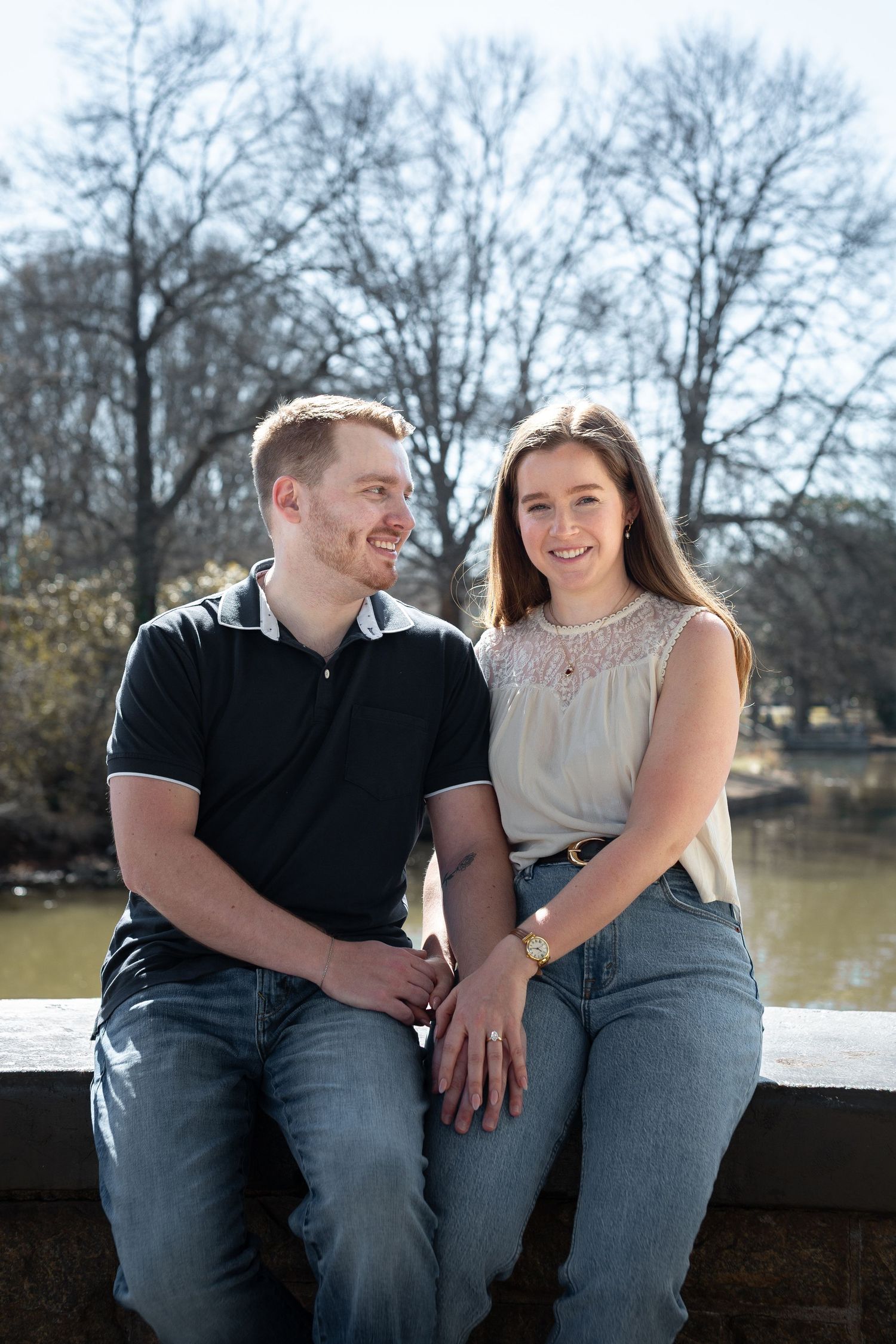 A couple sits together on a wooden bench by a lake sharing joyful moments and laughter.
