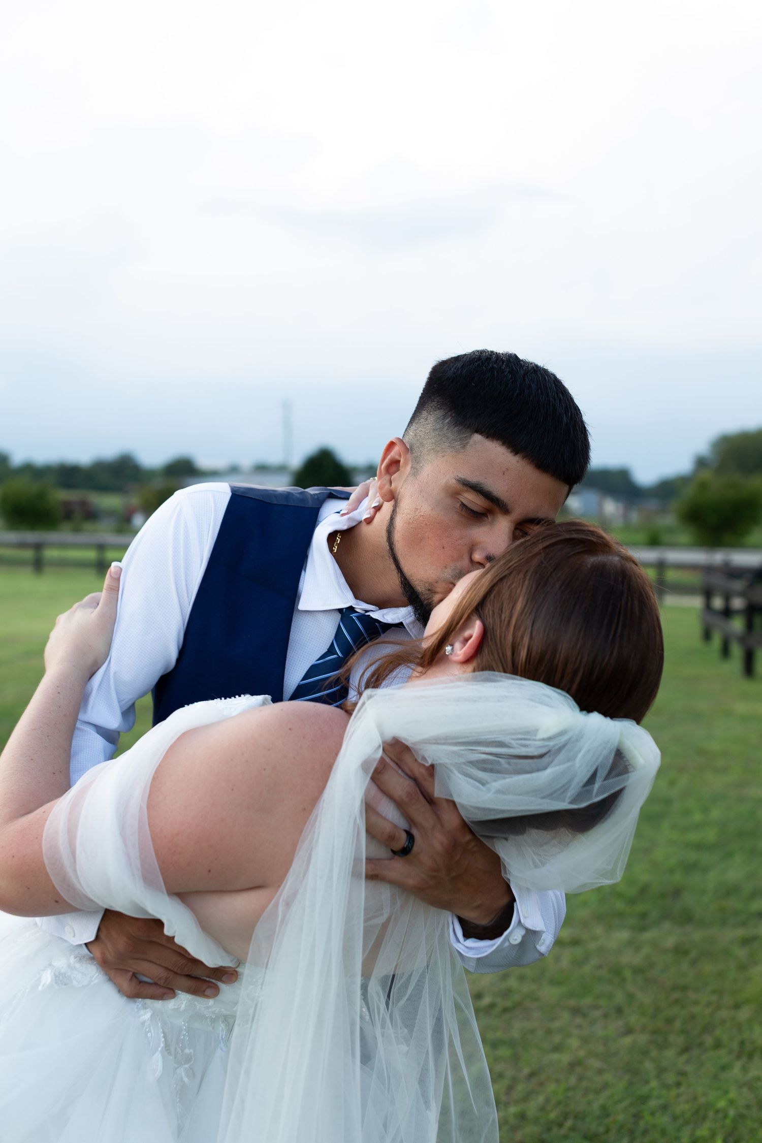 Romantic couple in wedding attire sharing an intimate moment in an outdoor field.