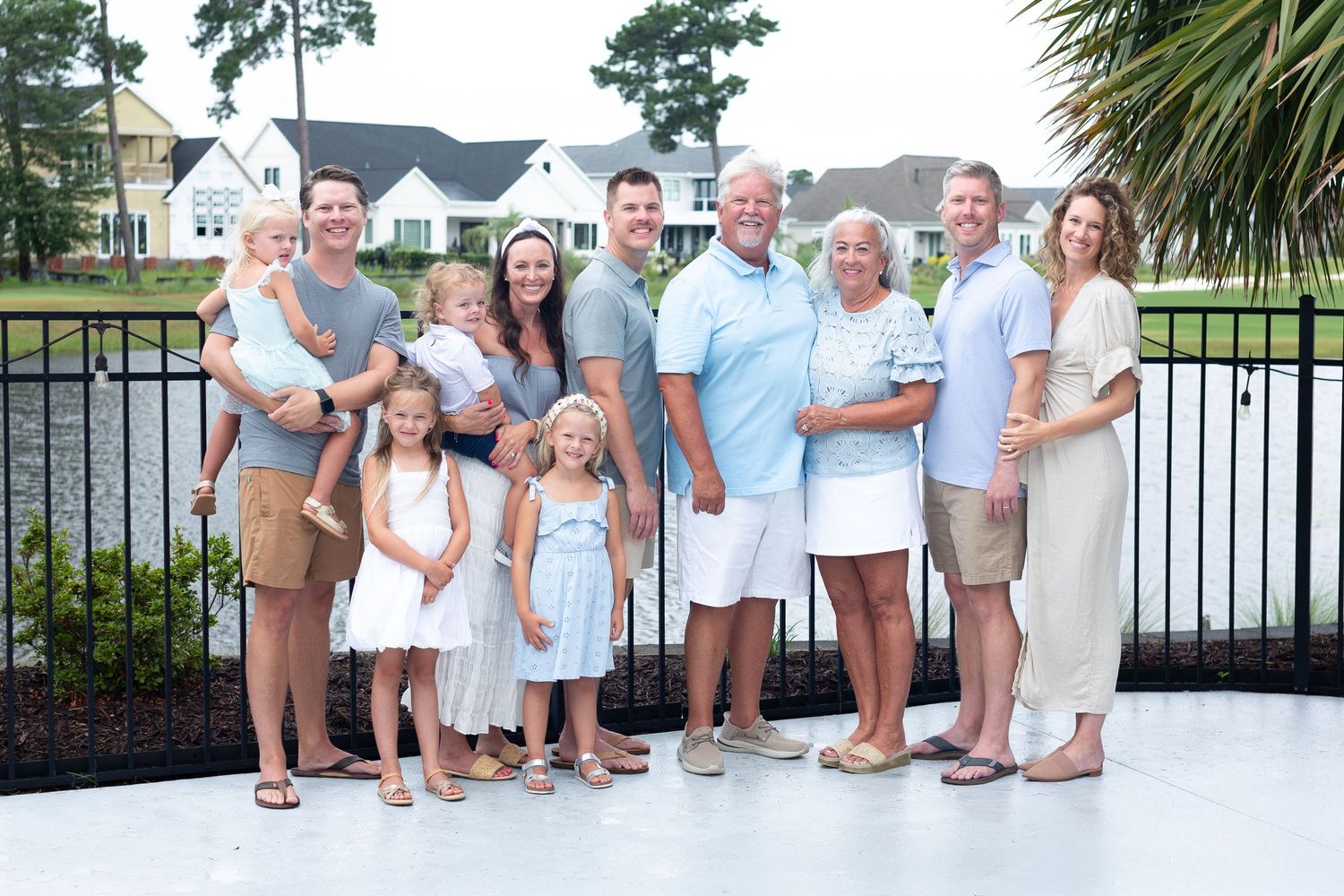 A group wearing coordinated white and blue outfits poses together for a casual outdoor family photo session.