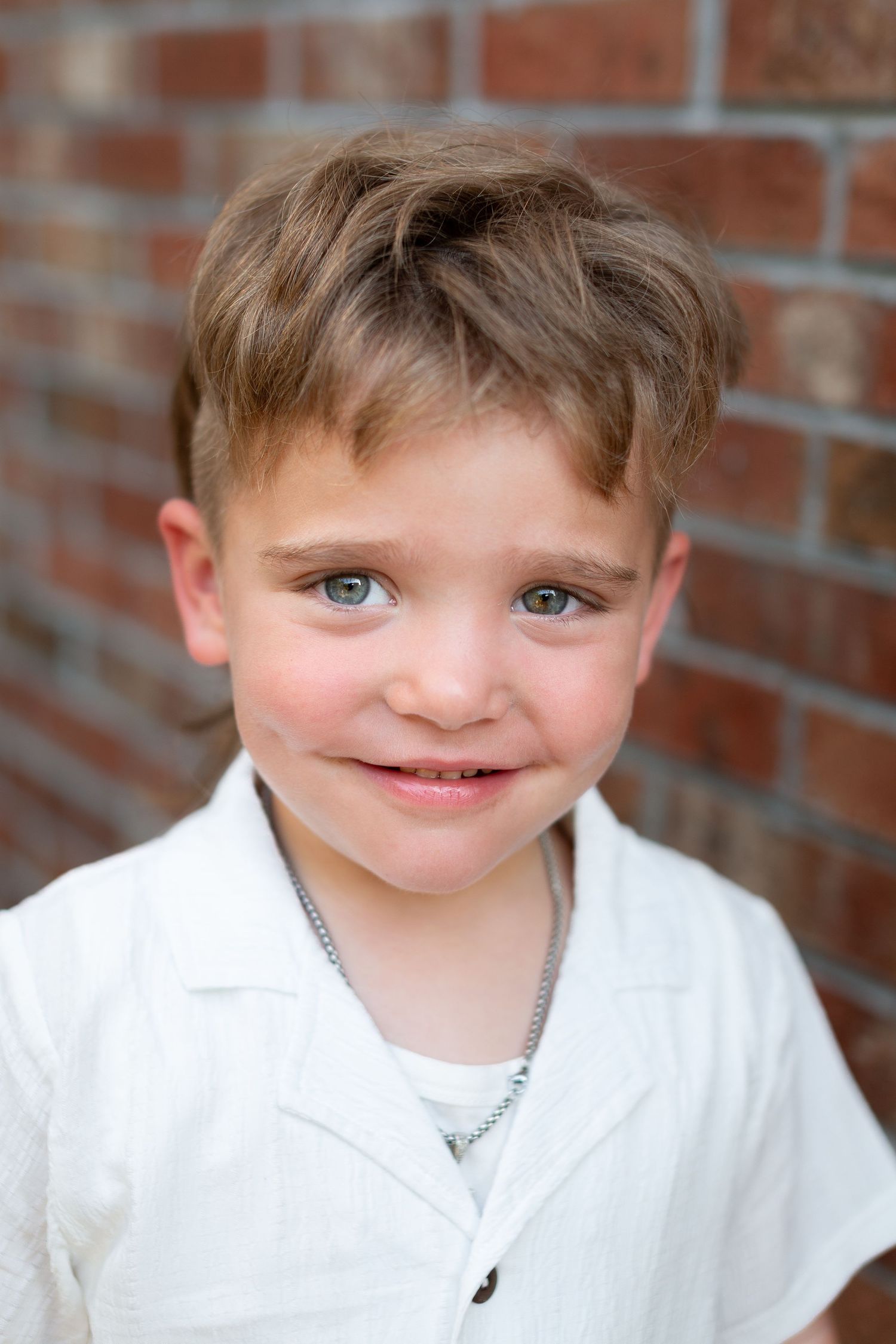 Series of close-up portraits against brick wall showing playful expressions.