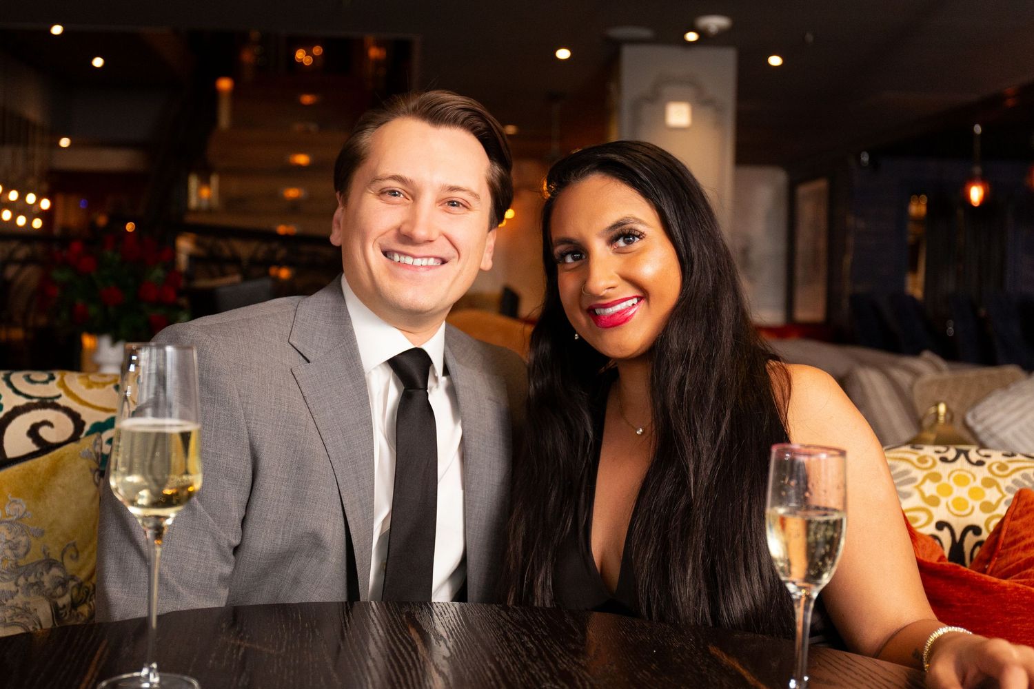 Guests enjoying drinks and conversation at an elegant evening wedding reception with warm lighting and formal attire.