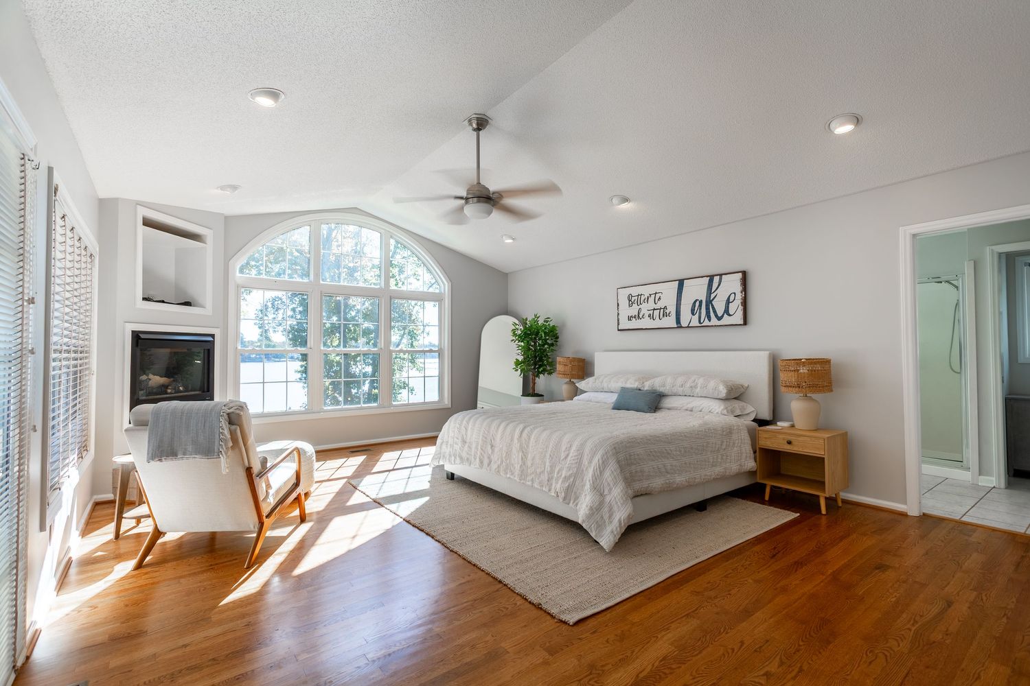 Panoramic view of a modern white bedroom with hardwood floors, arched windows, and minimalist decor.