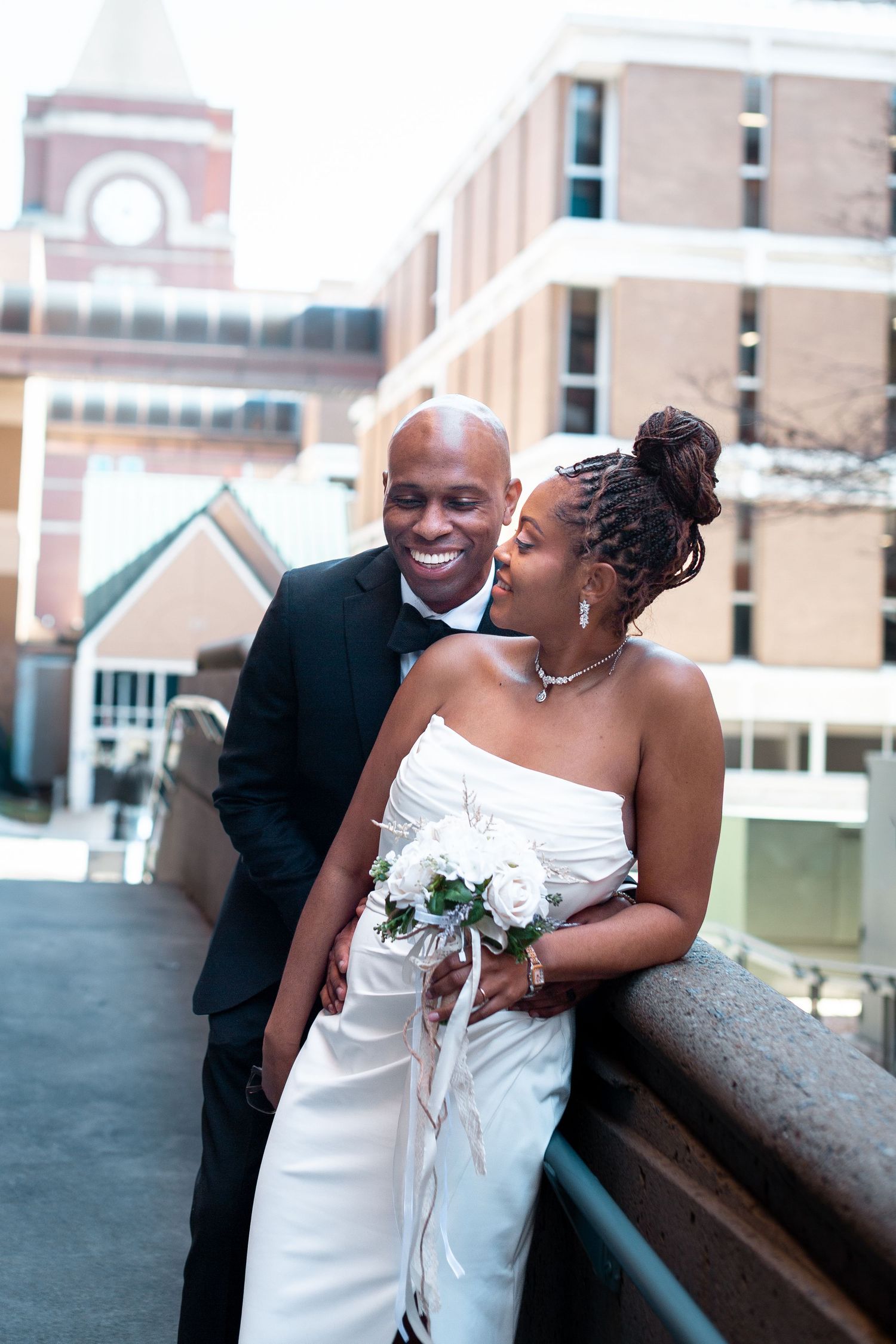 Happy newlyweds share romantic moments on a rooftop terrace during their wedding photoshoot.