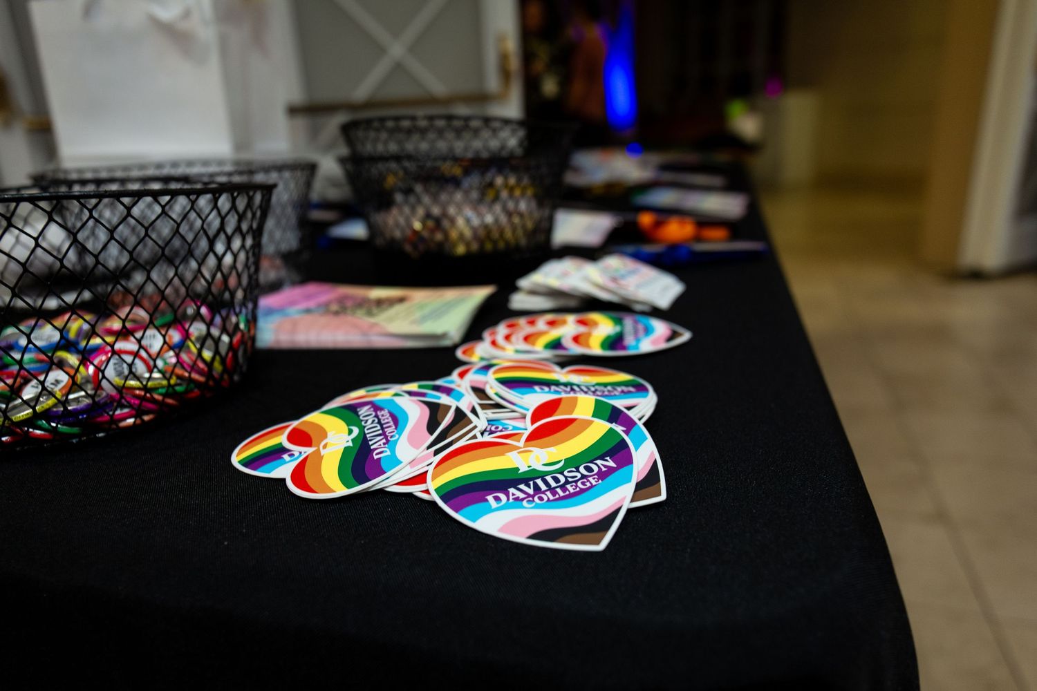 Colorful pride stickers and decorations arranged on a dark surface.