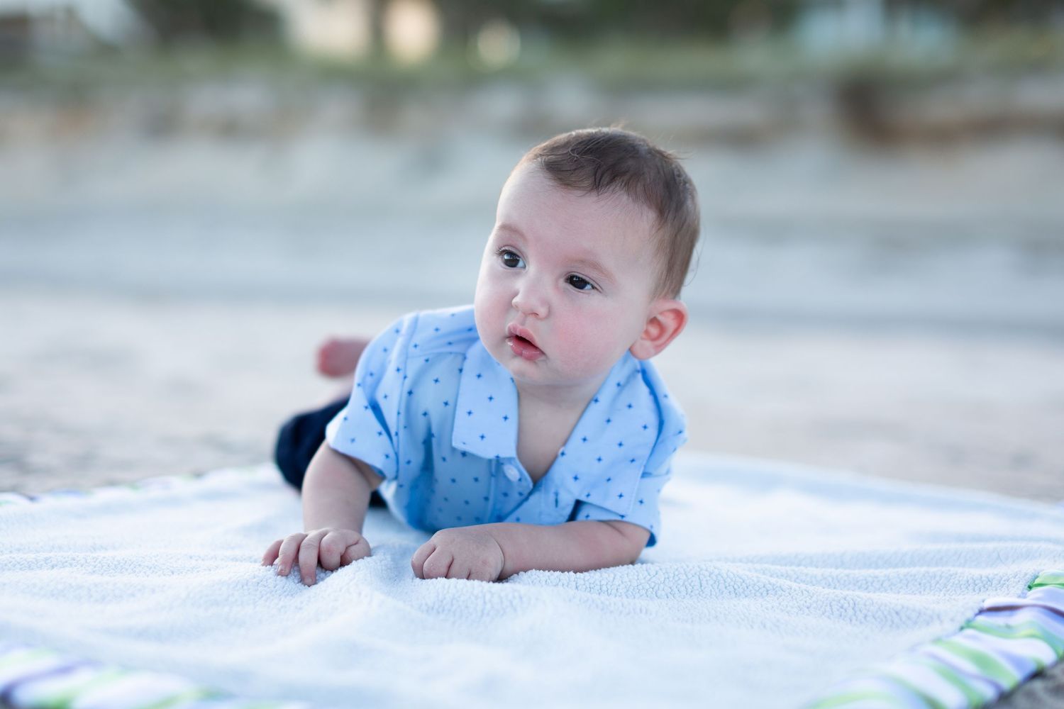 Baby lying on white blanket outdoors in various poses.