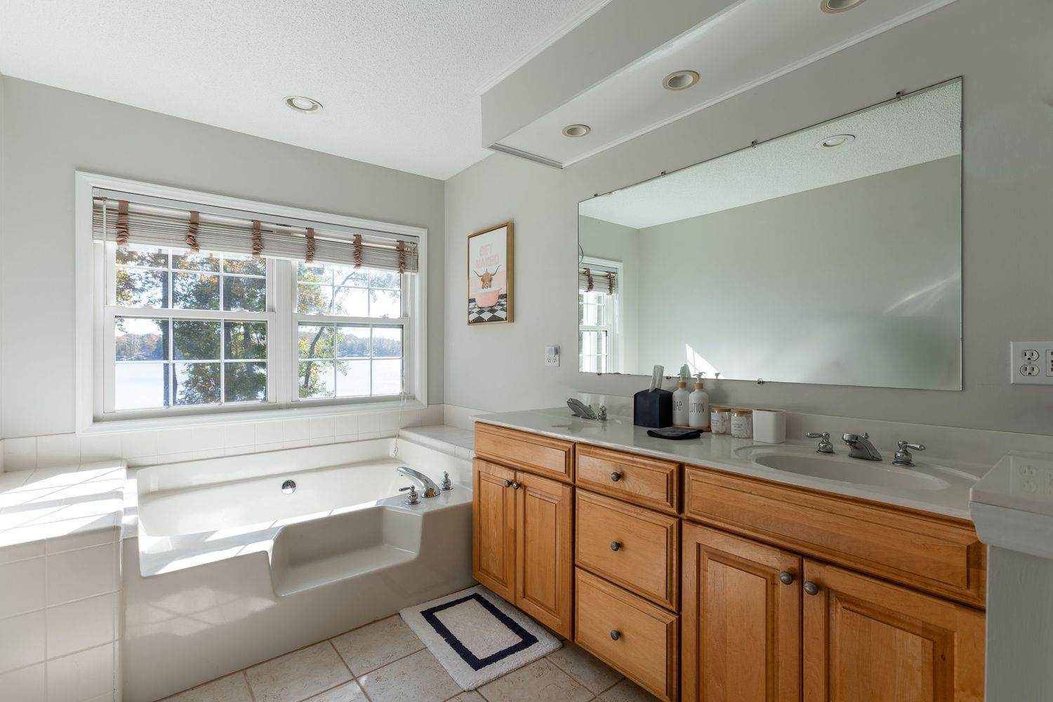Modern bathroom with white cabinetry, large windows, and natural light streaming in.