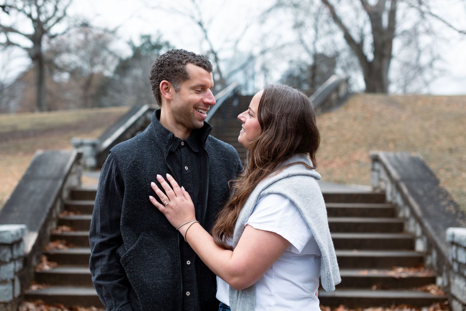 A couple shares a romantic moment on stone steps during an outdoor engagement photo session.